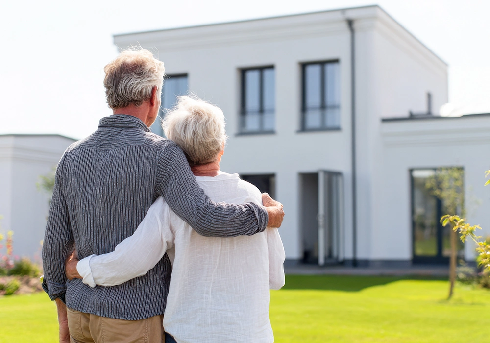 Back view of mature couple standing in front of large house